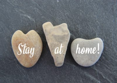 Gray background with 3 rocks which feature a text message: Stay At Home
